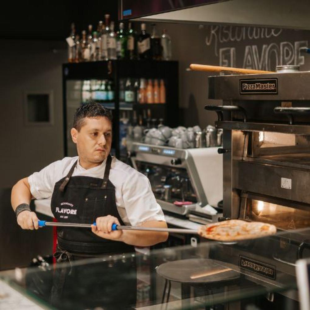 Flavore chef taking the pizza out of the oven