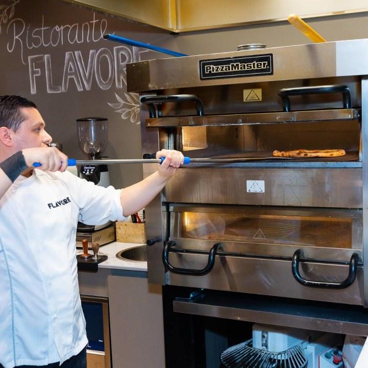 Flavore chef putting pizza in the oven