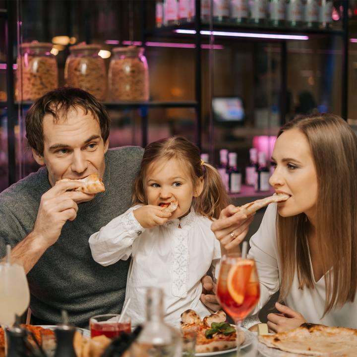 Perhe syömässä pizzaa pöydän ääressä