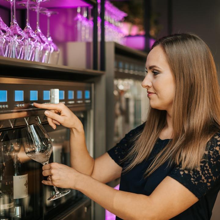 Woman pouring herself a glass of wine from a wine wall